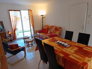 A dining area with a table set for four, a sofa, and a lamp. - Charming house in town center - 4 guests (Notre-Dame-de-Monts)
