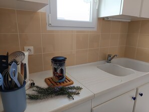 A kitchen with a sink, countertop, and a window above the sink. - Charming house in town center - 4 guests (Notre-Dame-de-Monts)