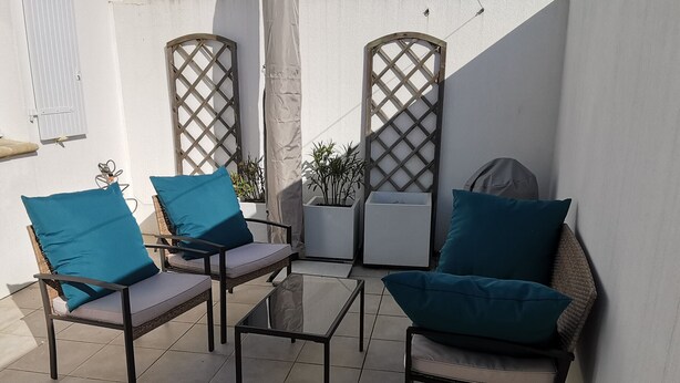 A patio area with two chairs and a table, a white wall, and a lattice gate. - House near city center - 8 guests (La Tranche-sur-Mer)