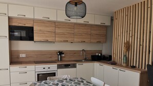 Moderni keittiö, jossa on puukuvioiset kaapit, sisäänrakennettu uuni ja ruokailutila, jonka päällä on kuvioitu pöytäliina.