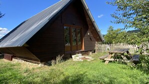 En stuga byggd av trä med ett sluttande tak, en trädörr och en liten veranda.