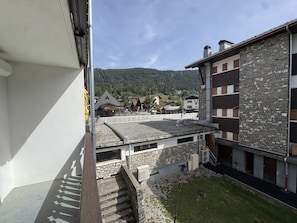 Ein Wohngebäude mit Stein-Fassade, geneigtem Dach und Blick auf eine gebirgige Landschaft im Hintergrund.