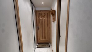A hallway with a wooden door, white walls, and a tiled floor. - Studio cabin in the center - 4 guests (Les Carroz d'Arâches)