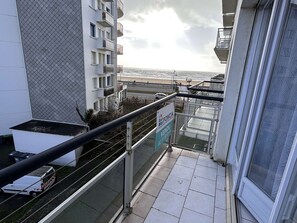 Ein Balkon mit Meerblick, ein Schild mit der Aufschrift 'VENDU' und ein Gebäude mit einer verzierten Fassade.