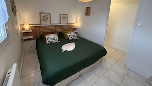 Un dormitorio con cama, lámparas de noche, lámpara colgante y cuadros en la pared.