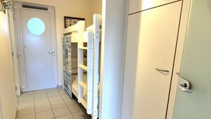 Ein schmaler Flur mit einer weißen Tür, einem weißen Kühlschrank und einem weißen Schrank.