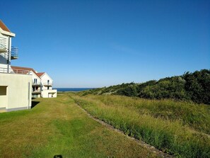 Ein Küstenwohngebiet mit modernen Häusern, einem Rasenweg und freiem Blick auf das Meer.