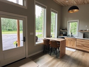 Una cocina moderna con encimera de madera, taburetes de bar y una lámpara colgante.