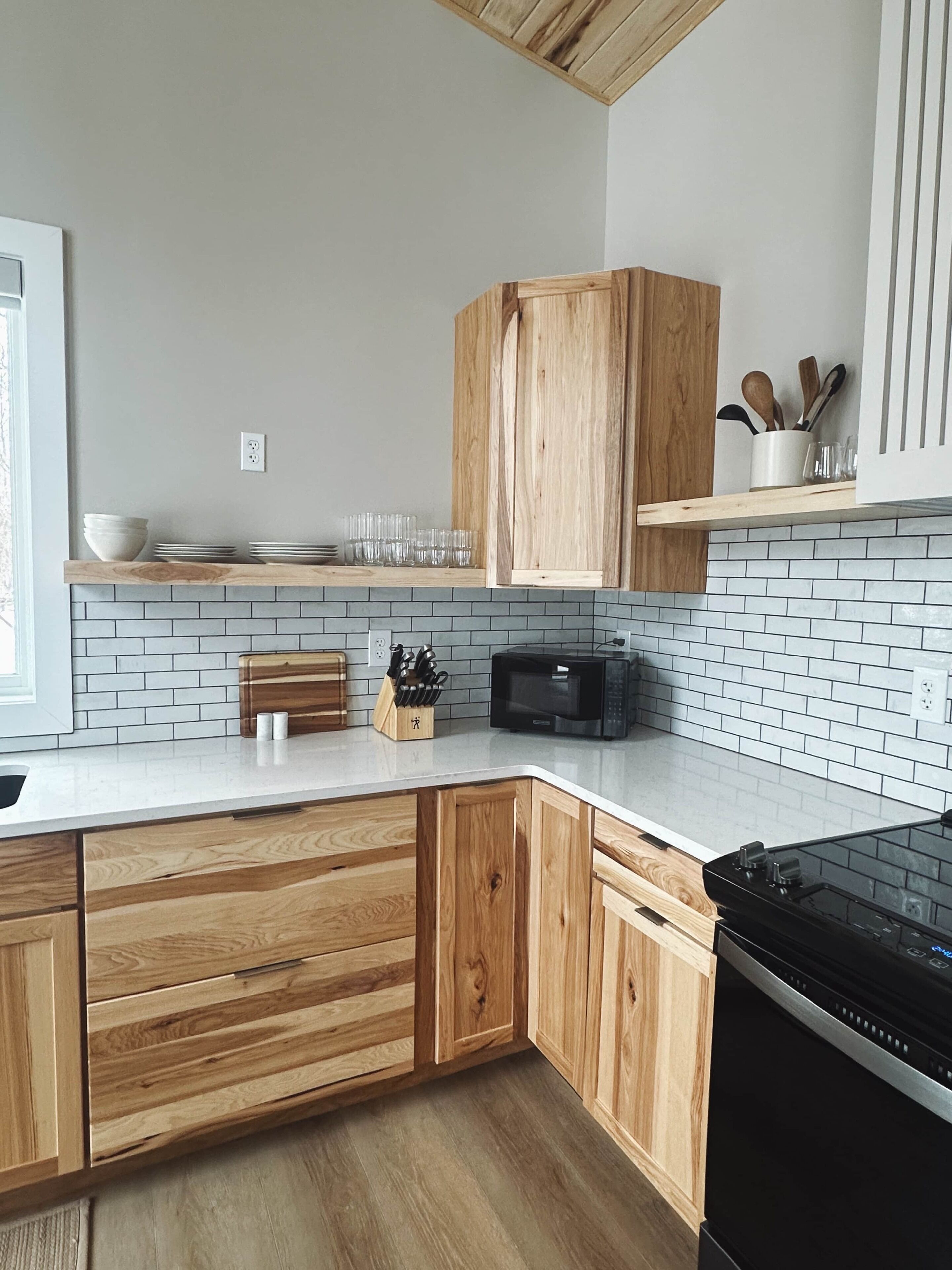 A kitchen with wooden cabinets, a microwave, and a black stove.