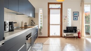 Eine moderne Küche mit dunklen Schränken, einem eingebauten Ofen, einer Kaffeemaschine und einem Fernseher auf einem weißen Schrank.