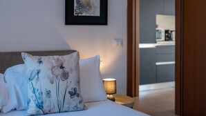 Ein Schlafzimmer mit einem Bett, Kissen, einem Nachttisch, einer Lampe und einem gerahmten Bild an der Wand.