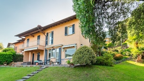 Ein zweigeschossiges Haus mit einem Balkon, einem kleinen Garten und einer Steintreppe, die zum Eingang führt.