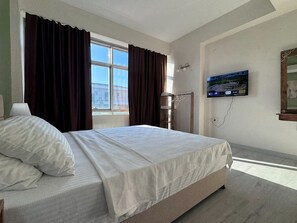 A hotel room with a bed, a TV mounted on the wall, and a window with curtains. - The New House Çeşme  (Cesme)