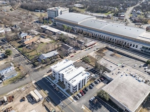 An aerial view of a commercial building with a large parking lot and a train station in the background. - Elegant New-Build Suite • Walk to Everything (Hot Springs)