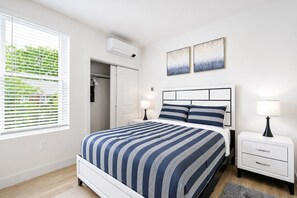 A bedroom with a bed, bedside tables, a wardrobe, and a window with blinds. - Elegant New-Build Suite • Walk to Everything (Hot Springs)