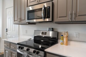 A modern kitchen with stainless steel appliances, including a microwave and an oven. - Elegant New-Build Suite • Walk to Everything (Hot Springs)