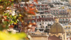A historic building with a dome and a clock tower, surrounded by densely packed buildings with balconies. - Room-terrazza del Sole - Camera Maestral (Positano)