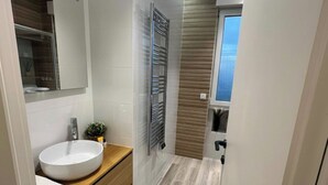 Een moderne badkamer met een wit wastafel, houten opbergmeubel en een handdoekhouder.