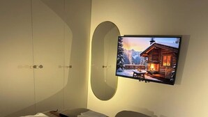 Een hotelkamer met een bed, een aan de muur bevestigde televisie en een grote spiegel.