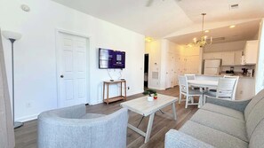 A modern living room with a sofa, a coffee table, and a TV mounted on the wall. - Sunny River Oaks Retreat  2BR Golf Condo (Myrtle Beach)
