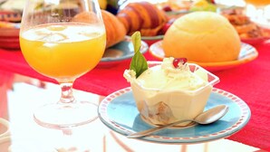 A breakfast setting with a glass of orange juice, a bowl of yogurt with fruit, and pastries on a table. - Room-terrazza del Sole -camera Levante (Positano)