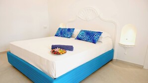 A bed with a white and blue headboard, two blue patterned pillows, a white mattress, and a small fruit bowl on the bed. - Room-terrazza del Sole -camera Levante (Positano)