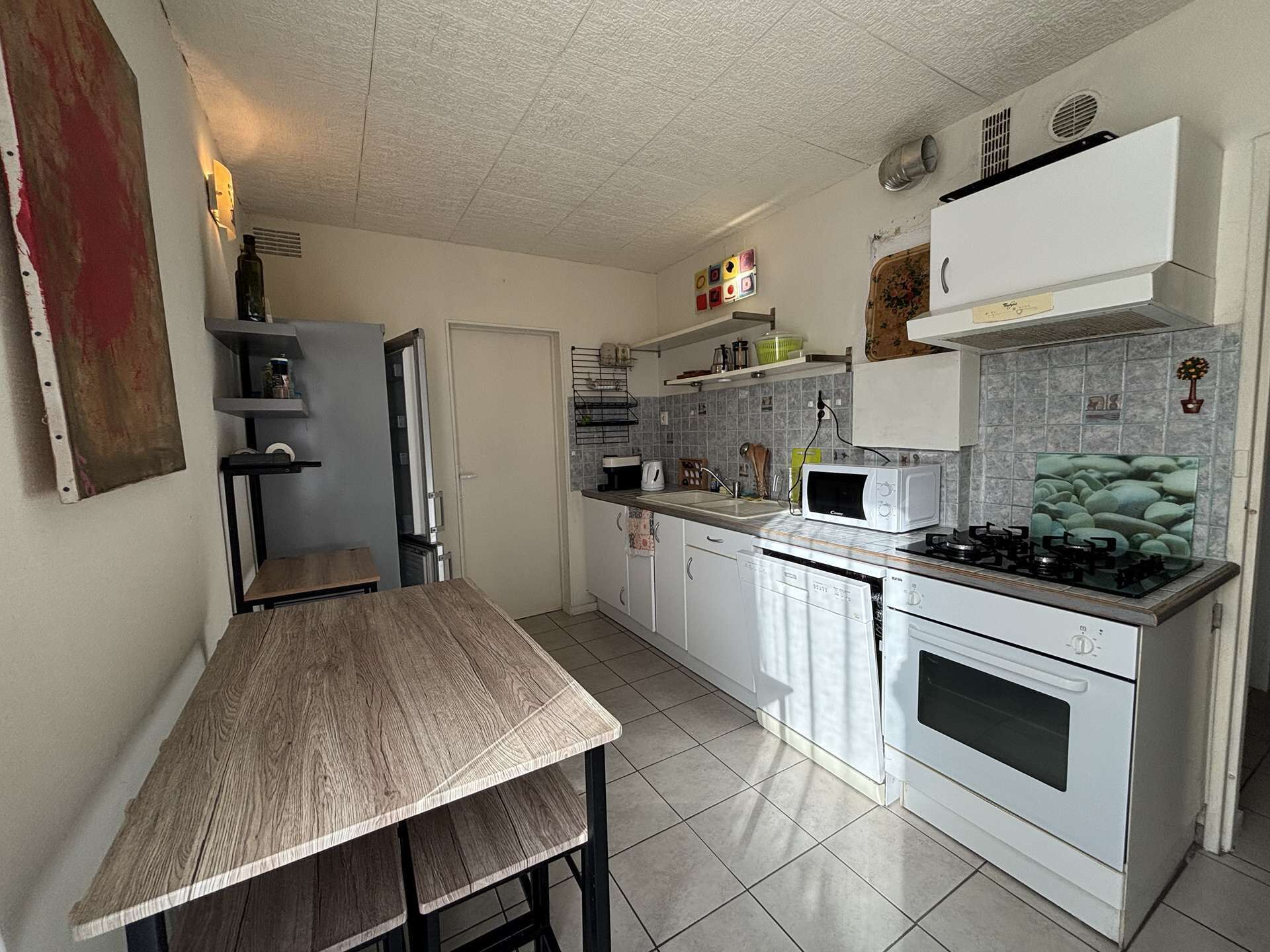 A compact kitchen with white cabinets, a gas stove, a microwave, and a sink.