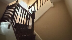 A staircase with wooden balusters and a handrail, leading to an upper floor.