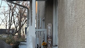 A house with a porch, a welcome sign, and a car parked in the driveway.