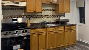 A kitchen with wooden cabinets, a stainless steel stove, and a tiled backsplash.