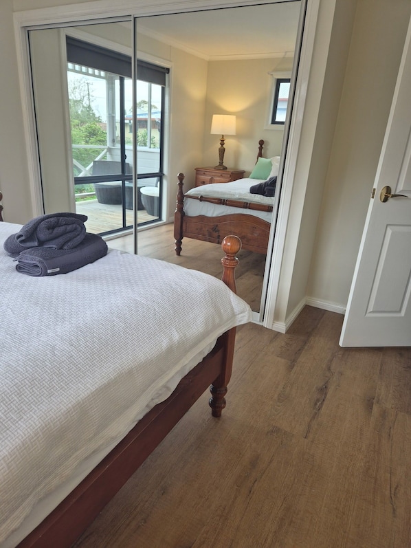 Un dormitorio con una cama de madera, un espejo y vistas a un patio exterior.
