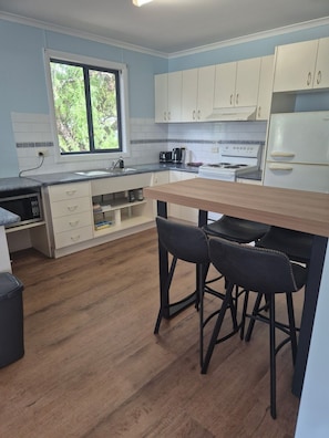 Una cocina moderna con armarios blancos, encimera de madera, estufa integrada y ventana con vistas al verdor.
