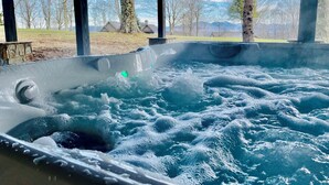 Un jacuzzi con vistas a árboles y montañas al fondo.
