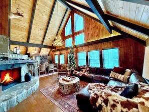 Ein geräumiges Wohnzimmer mit Kamin aus Stein, Ledersofa und Weihnachtstanne.