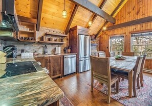 Eine rustikale Küche mit Holzbalken, einer Marmorarbeitsplatte und einem Essbereich mit Tisch und Stühlen.