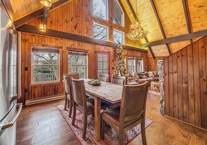 Ein geräumiger Essbereich mit Holztisch und Stühlen, großen Fenstern und einer Kandelaber.