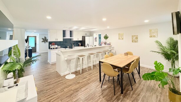 A modern kitchen with white cabinets, a central island, and bar stools. - Salt water beach/City vibe vacation home. (Largo)