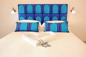 A neatly made bed with a blue and white headboard, two matching pillows, and a rolled white towel with silver jewelry. - Villa Esclusiva con Vista Panoramica su Positano (Positano)