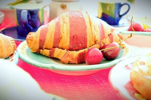 Ein Croissant mit roter Füllung und einer Kirsche auf einem Teller.