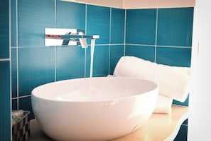 Ein Badezimmer mit einem großen weißen Waschbecken, einem Wasserhahn und einem Handtuch auf der Ablagefläche.