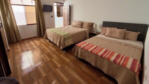 Une chambre d’hôtel avec deux lits, une télévision, une armoire et une fenêtre avec des rideaux.