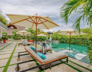 A poolside area with lounge chairs, umbrellas, and a clear view of the pool.