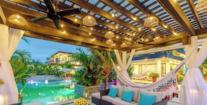 A poolside area with a hammock, outdoor seating, and a view of a building in the background.