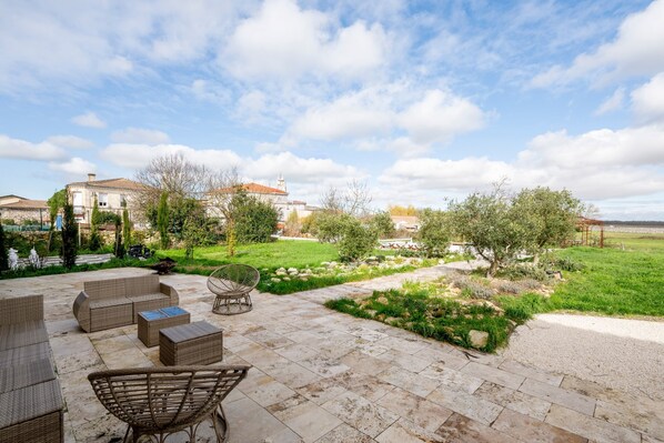 Un patio al aire libre con muebles de mimbre, un camino de piedra y una vista de una casa grande al fondo.