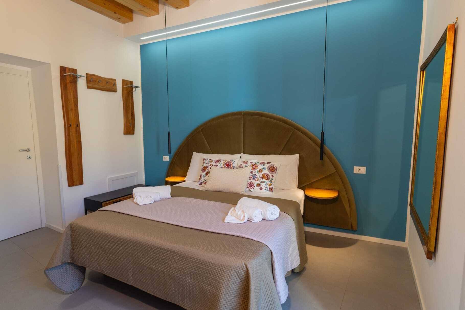 A bedroom with a bed, bedside tables, a blue accent wall, and wooden decor.