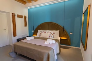 A bedroom with a bed, bedside tables, a blue accent wall, and wooden decor.