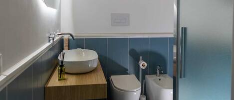 Ein Badezimmer mit Holzboden, zwei Waschbecken, einer Toilette und einem Fußboden mit Musterfliesen.