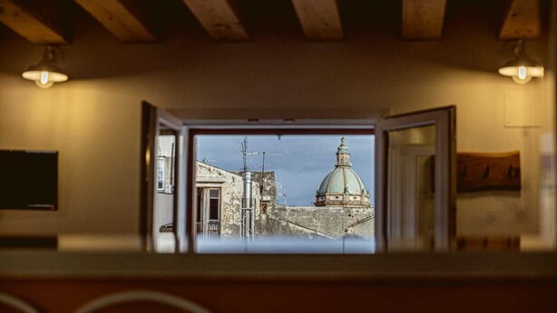 A view through a doorway to an urban landscape with a prominent dome structure. - Panormos 91 Rooms & Terrace (Palermo)