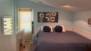 Quarto com cama, penteadeira, espelho e ar condicionado fixado na parede.