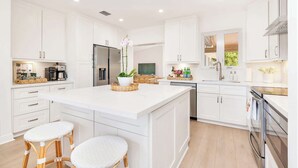 Una cocina moderna con armarios blancos, una isla central y un horno empotrado.
